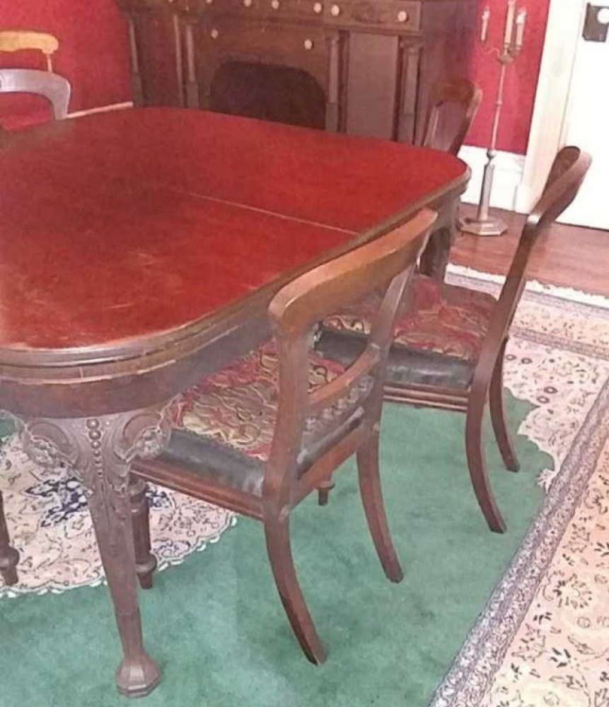 Antique Dining Table. Table is approx. 56" x 48" and is believed to be Walnut. Table has a date of 1925. There is an extra leaf but it is not an original.